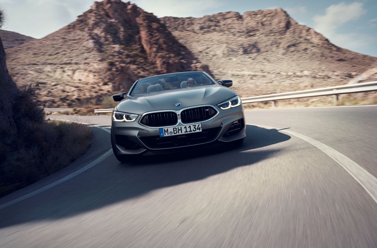 A gray BMW 8 Series M850i xDrive Convertible model turning along a stretch of desert highway