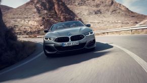 A gray BMW 8 Series M850i xDrive Convertible model turning along a stretch of desert highway