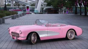A pink 1956 Chevrolet Corvette C1 from the film "Barbie," parks next to the London Eye.
