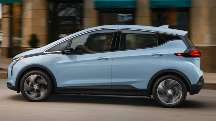 A blue 2023 Chevrolet Bolt EV is driving on the road.