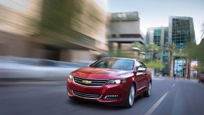 A red Chevrolet Impala blasts down a city street.