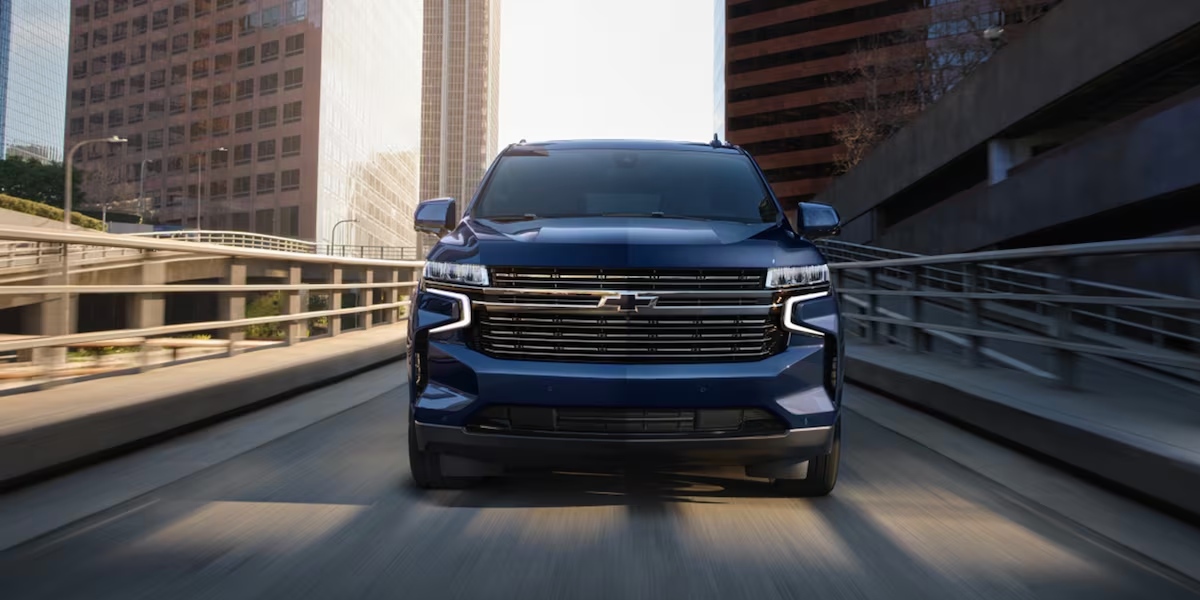A blue 2023 Chevrolet Tahoe full-size SUV is driving on the road.