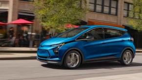 A blue 2023 Chevy Bolt EV is driving on the road.