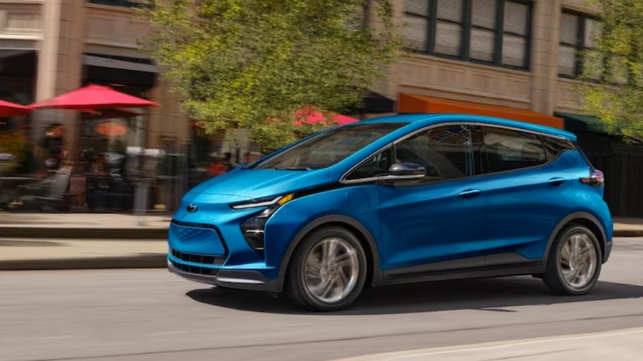 A blue 2023 Chevy Bolt EV is driving on the road.