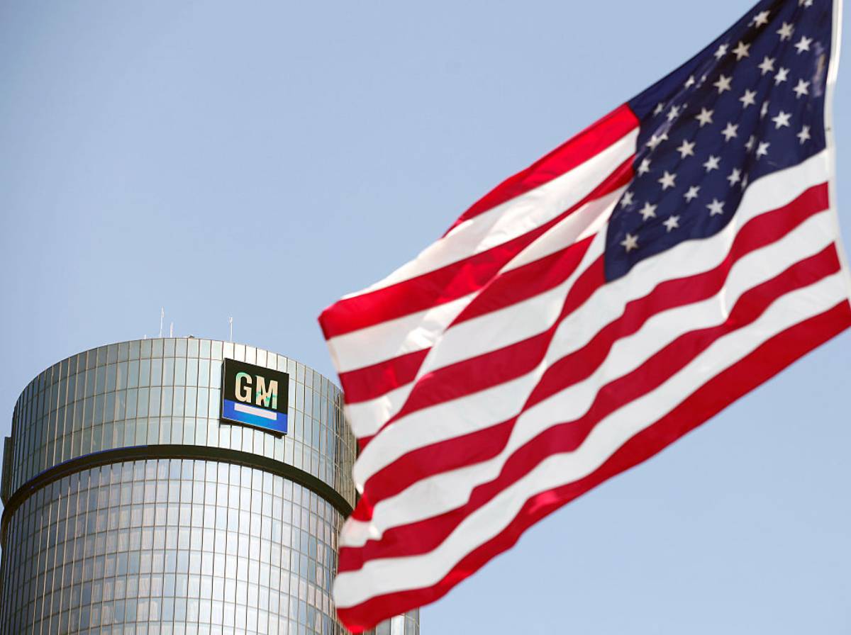 A flag waving outside of a building with a General Motors logo.