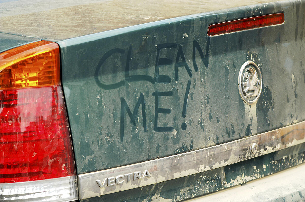 Dirty car trunk with "clean me" written on it
