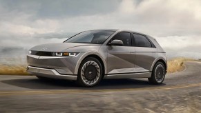 A gray 2023 Hyundai Ioniq 5 small electric SUV is driving on the road.