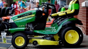 A lineup of yellow and green John Deere riding mowers sit on a platform.