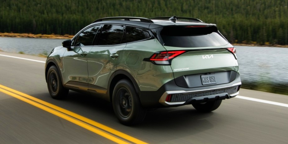 The rear of a green 2023 Kia Sportage small SUV driving on the road. 