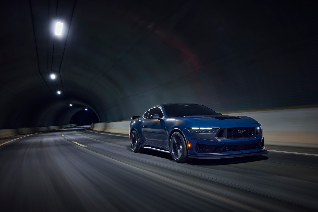 A Blue Ember Metallic 2024 Ford Mustang Dark Horse drives through a tunnel.