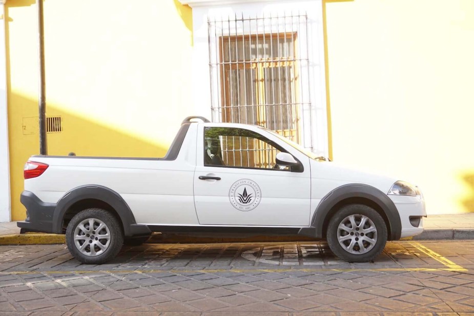 A white Ram 700 compact pickup truck with a short "regular" cab parked in front of a yellow wall in Mexico.