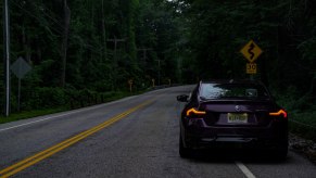 A BMW M240i parked in front of a curvy road sign