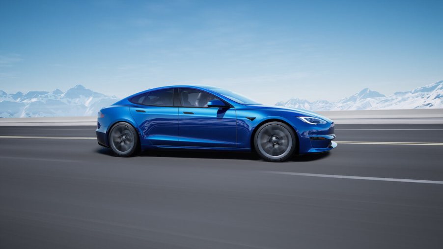 A blue Tesla Model S drives down the street