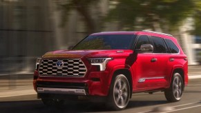 A red 2023 Toyota Sequoia full-size SUV is driving on the road.
