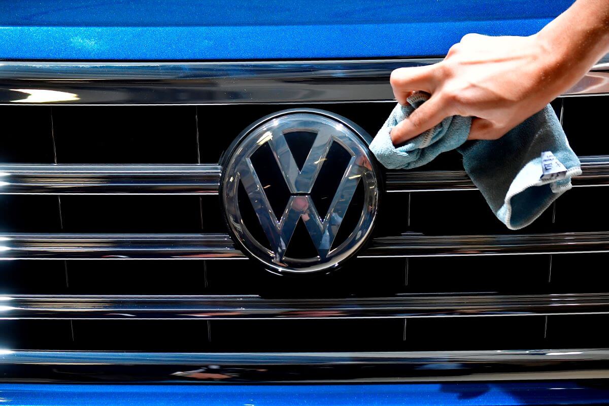 Someone wiping down the shining grill of a blue Volkswagen Touareg crossover SUV model