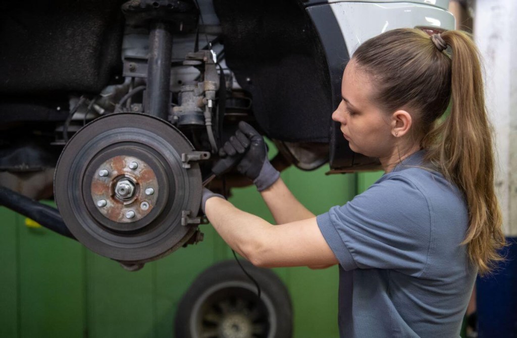 A mechanic changing the brake disc on a Land Rover Range Rover Evoque model in a workshop garage