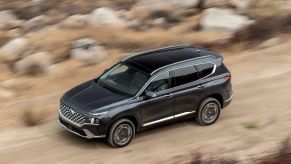 An overhead shot of a 2023 Hyundai Santa Fe midsize SUV model driving through a desert with a blurred background