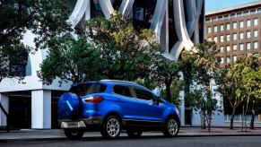 A rear shot of the trunk and spare tire on a blue 2021 Ford EcoSport subcompact SUV model parked in a city