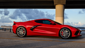 A 2024 Chevy Corvette Stingray performance sports car coupe model in Torch Red parked under a highway bridge