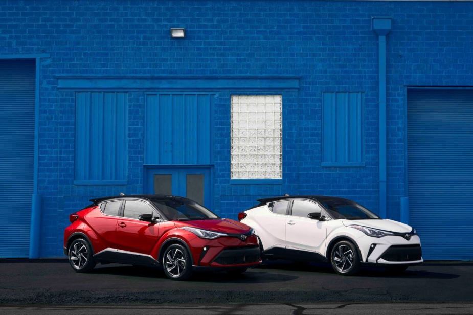 Red and white 2022 Toyota C-HR subcompact crossover SUV models parked in front of a blue painted brick wall
