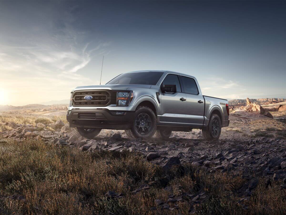 A 2023 Ford F-150 Rattler full-size pickup truck model driving over dirt and rocks in a desert wilderness terrain