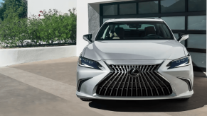 A 2024 Lexus ES Hybrid midsize executive car/luxury sedan model parked outside of a garage door