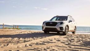 A 2023 Subaru Forester compact crossover SUV model parked on a sandy beach covered in tire treads
