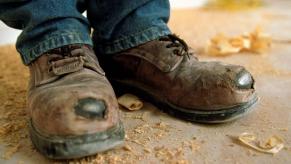 A pair of worn and torn work shoes, which aren't the same as a motor vehicle's dust boot
