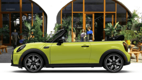 A banner of a side profile 2024 Mini Convertible model parked in front of a café restaurant patio