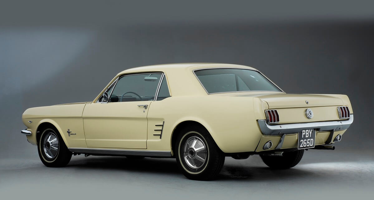 A cream-colored classic Mustang shows off its coupe styling.