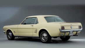 A cream-colored classic Mustang shows off its coupe styling.