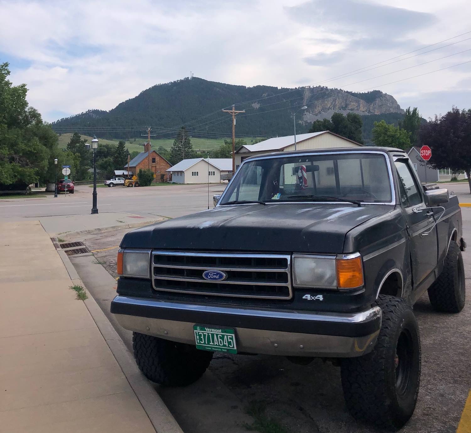 An old black Ford F-150 pickup truck parked in front of a mountain in Sundance, Wyoming.
