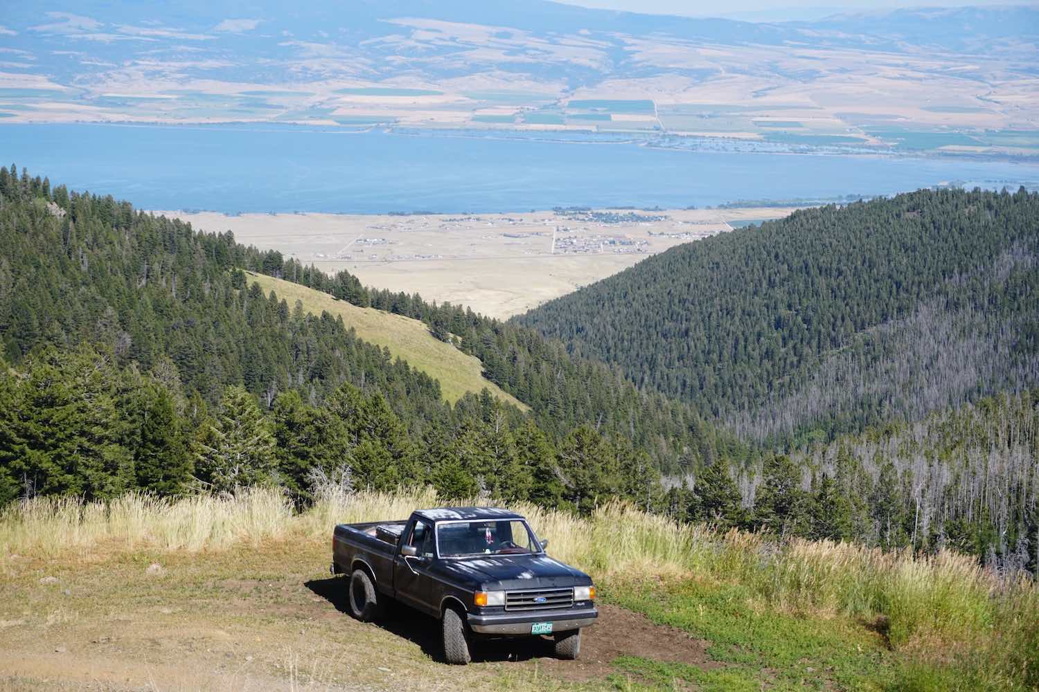 1988 Ford F-150 classic old truck parked on a mountainside in Montana, a lake visible in the background.