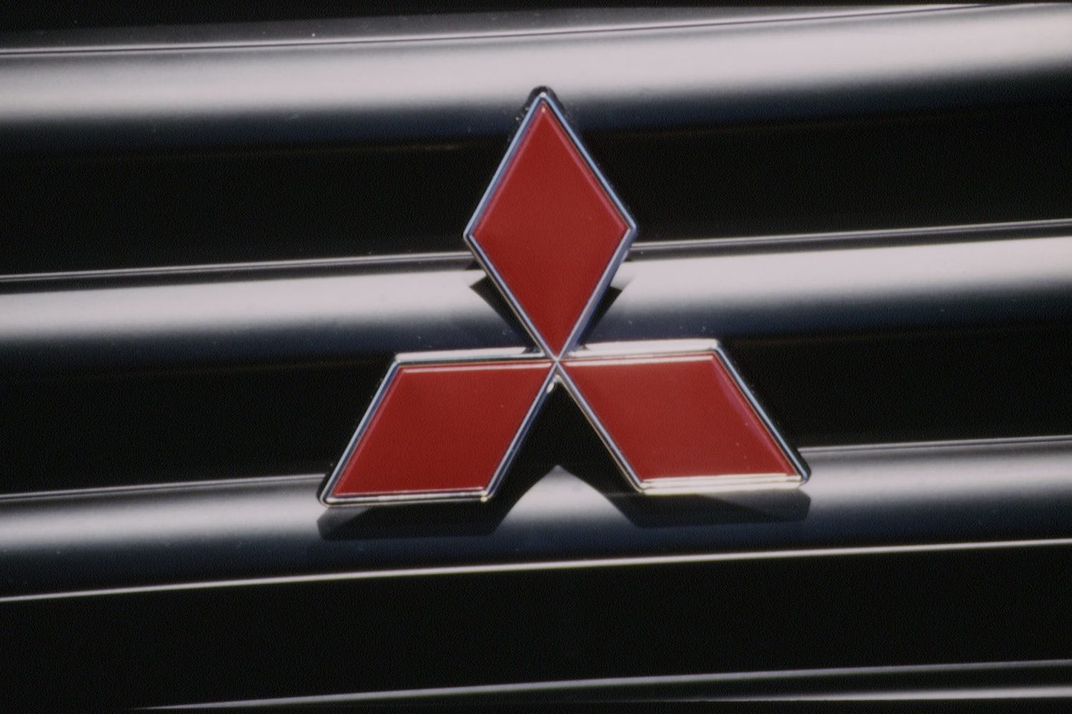The Mitsubishi logo on an old Mighty Mountain Max 4WD compact pickup truck's grille.