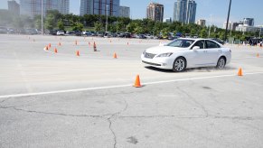 A white 2010 Lexus ES, one of the best used midsize luxury cars, in a parking lot with cones.