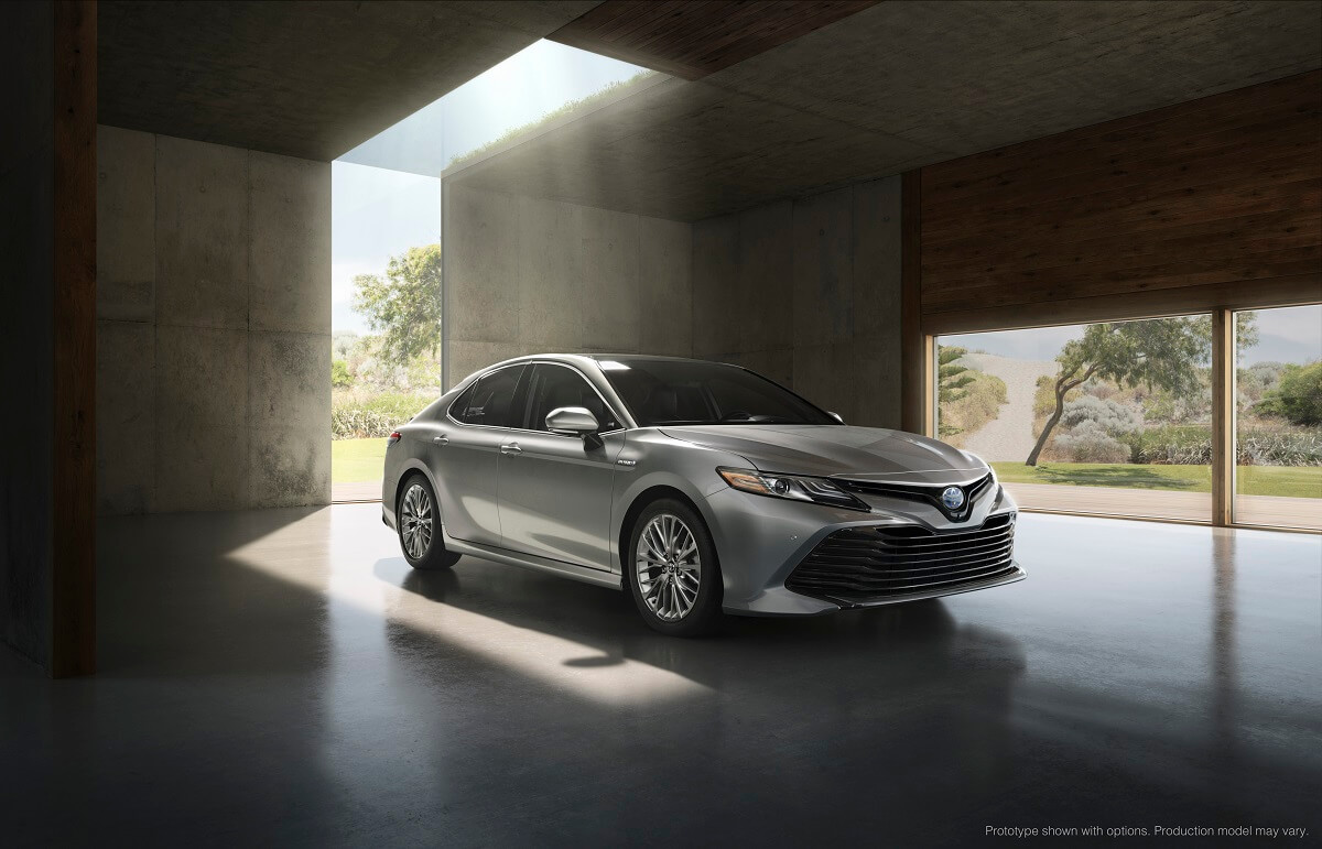 A silver 2018 Toyota Camry, a used car with a rising price, parks under sunlight.