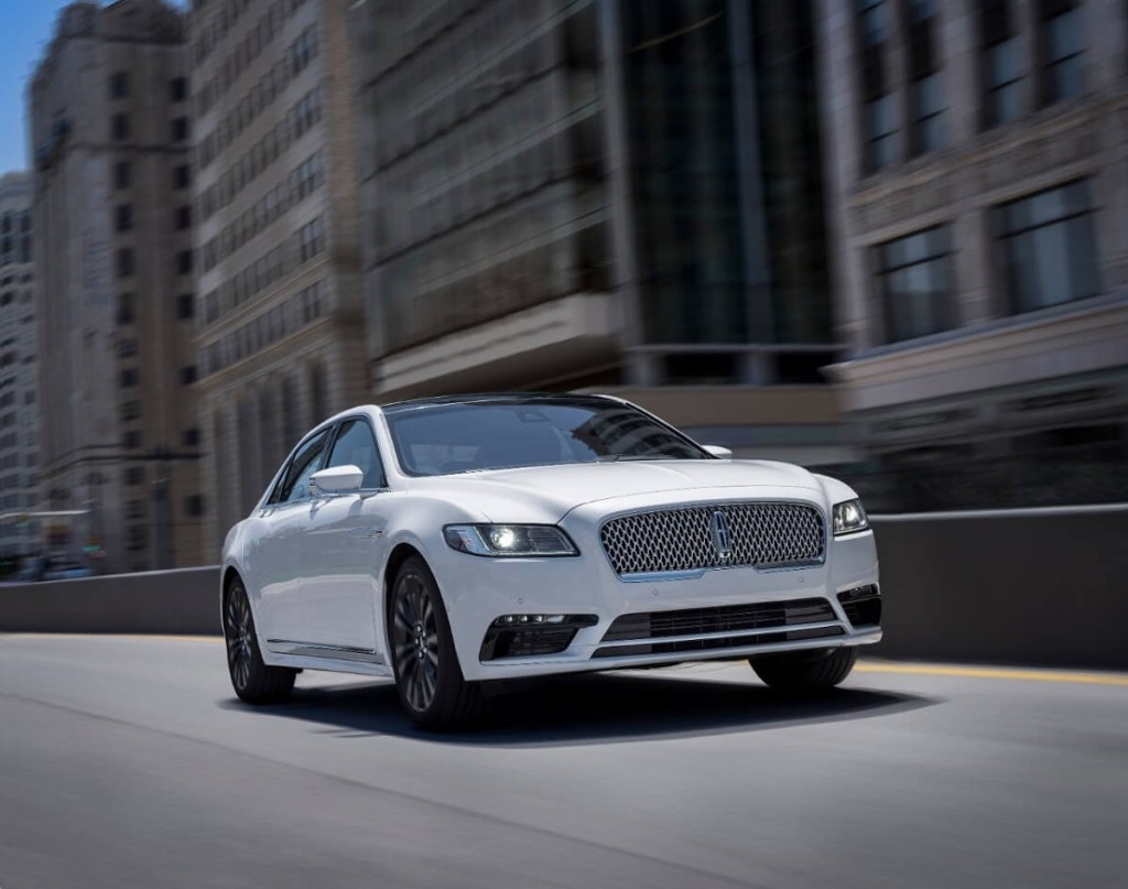 A white 2020 Lincoln Continental drives on urban roads.