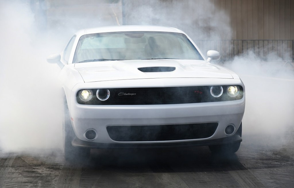 A white 2023 Dodge Challenger R/T Scat Pack does a burnout on the dragstrip.