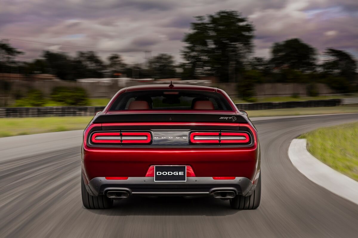 A dark red Dodge Challenger SRT Hellcat drives around a corner on a track. 