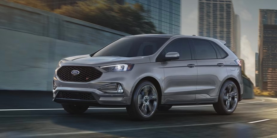 A gray 2023 Ford Edge midsize SUV is driving on the road. 
