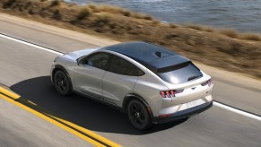 A white 2023 Ford Mustang Mach-E is driving on the road.