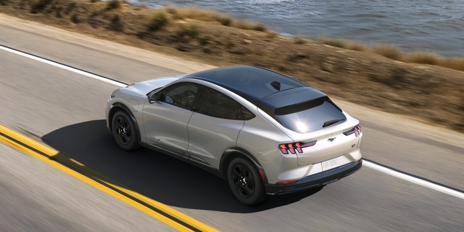A white 2023 Ford Mustang Mach-E is driving on the road. 
