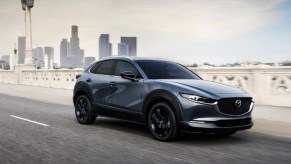 A blue 2023 Mazda CX-30 subcompact SUV is driving on the road.