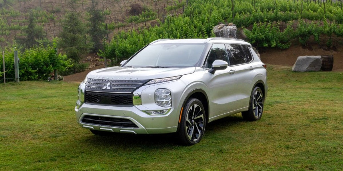 A white 2023 Mitsubishi Outlander small SUV is parked outside.