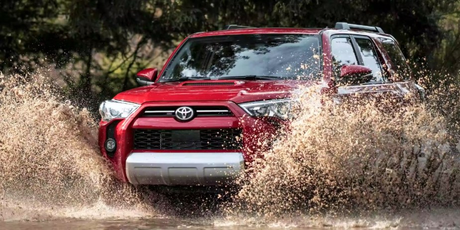 A red 2023 Toyota 4Runner midsize SUV is driving off-road.