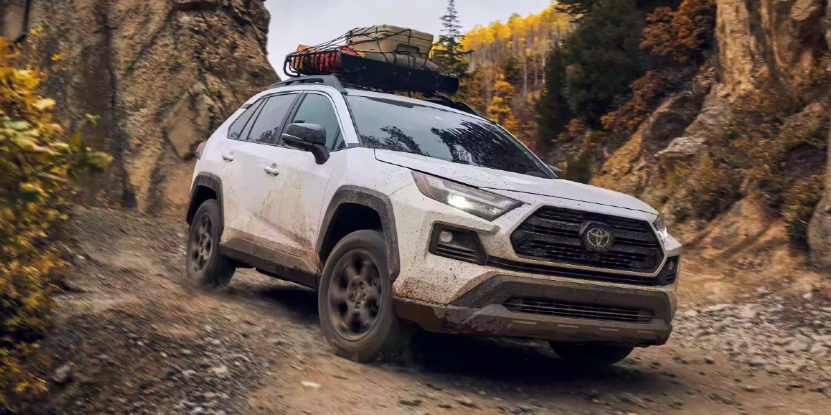 A white 2023 Toyota RAV4 small SUV is driving off-road.