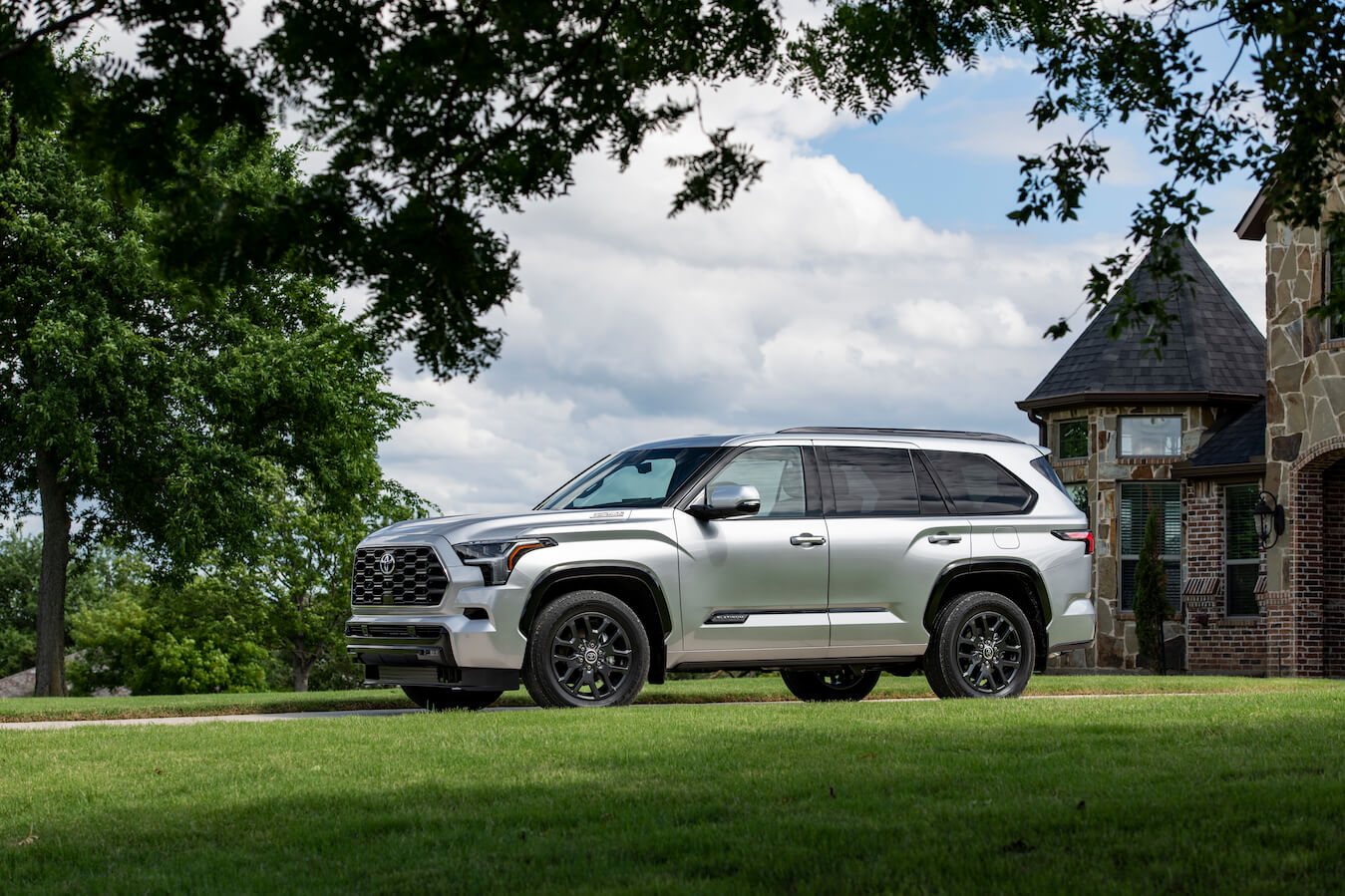 A silver 2023 Toyota Sequoia Platinum parked in front of a mansion. The Platinum is the most popular 2023 Toyota Sequoia trim.