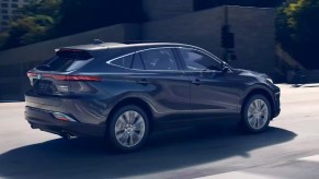 A gray 2023 Toyota Venza Limited hybrid SUV is driving on the road.