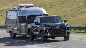 A black Toyota Tundra towing an Airstream RV. The Tundra and Silverado are two truck competitors in the same class.