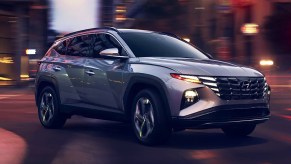 A gray 2024 Hyundai Tucson small SUV is driving on the road.